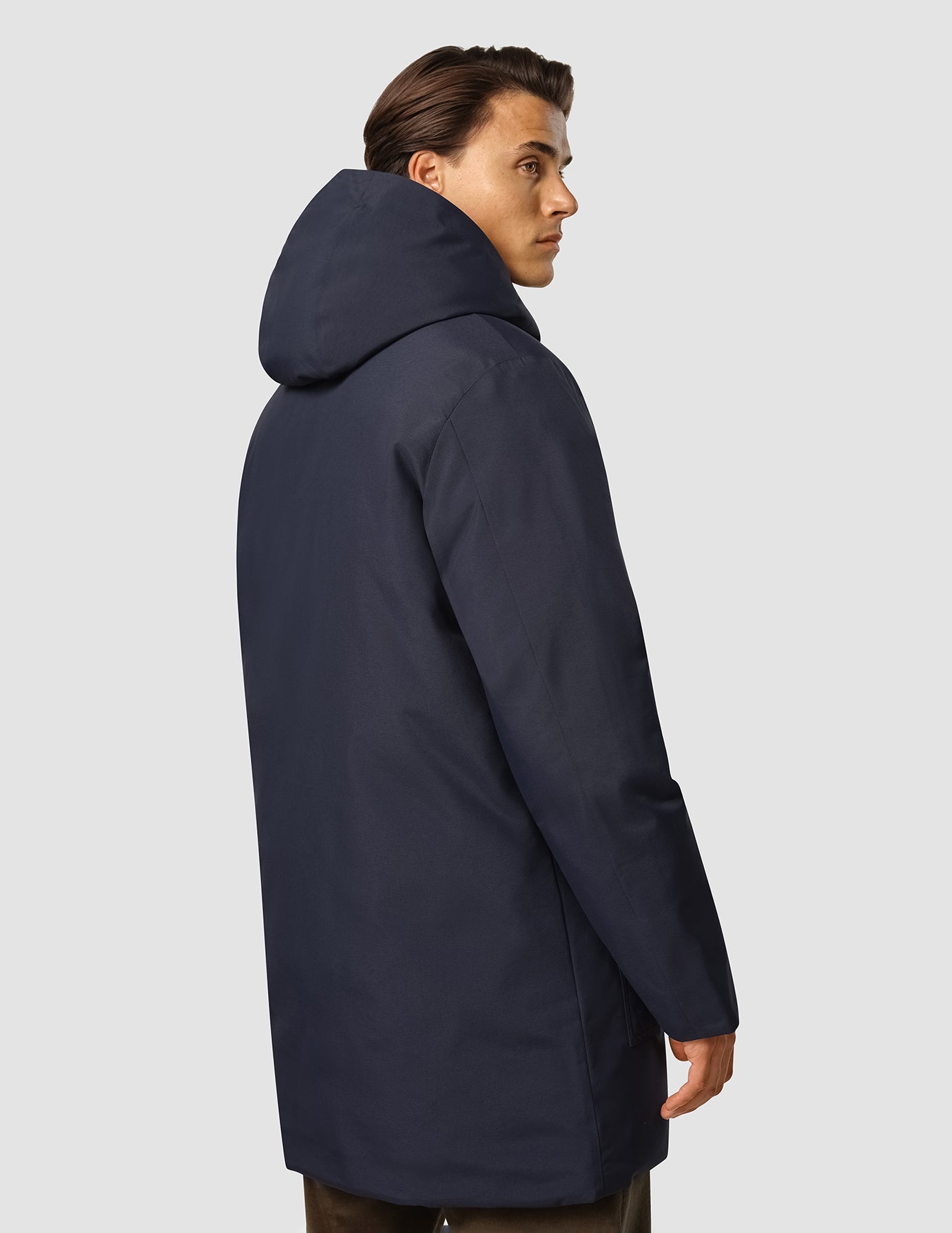 Eine Person, die eine wasserdichte, dunkelblaue Utility-Jacke mit Kapuze trägt.